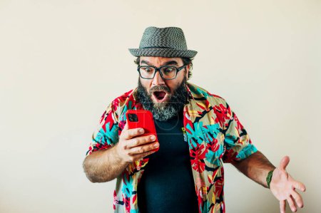 Téléchargez les photos : Gros homme avec une barbe et exalté avec téléphone intelligent. - en image libre de droit