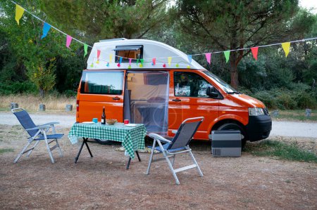 Téléchargez les photos : Camionnette camping-car sur le terrain avec chaises et table pour les loisirs. concept de vie van . - en image libre de droit