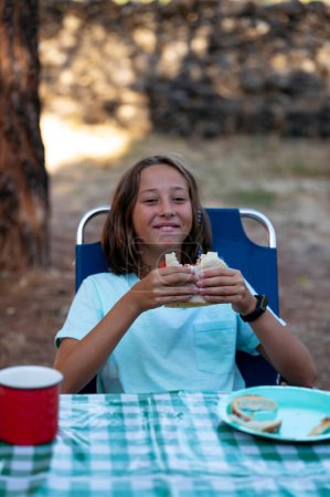 Photo for Little girl with sandwich on a camping day. - Royalty Free Image