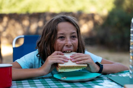 Téléchargez les photos : Petite fille avec sandwich sur une journée de camping. - en image libre de droit