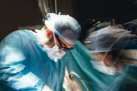 Foto de Motion photography with slow exposure of the doctor with mask doing a surgery. Emergency effect. - Imagen libre de derechos