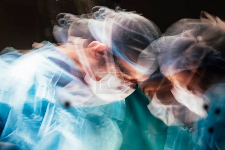 Foto de Motion photography with slow exposure of the doctor with mask doing a surgery. Emergency effect. - Imagen libre de derechos
