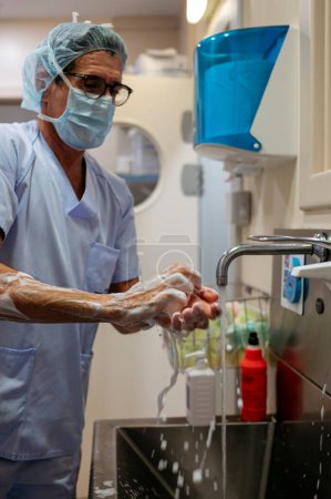 Téléchargez les photos : Docteur se lave les mains dans la salle d'opération. - en image libre de droit