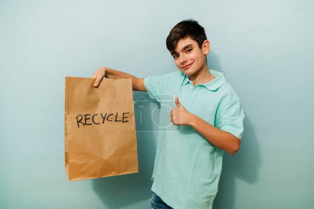 Photo for Young boy recycling with paper bag in studio. - Royalty Free Image