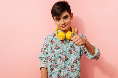 Foto de Joven con auriculares amarillos en estudio sobre fondo rosa. - Imagen libre de derechos