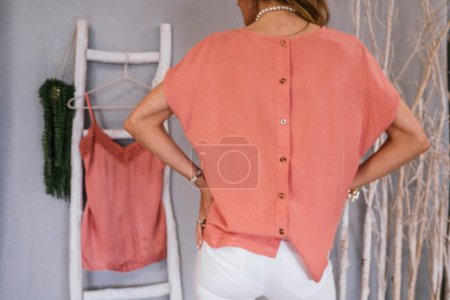 Téléchargez les photos : Femme montrant des vêtements qu'elle veut vendre d'occasion sur un site de vêtements usagés. - en image libre de droit