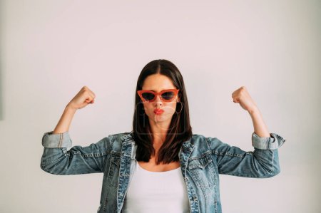 Photo for Woman with black hair flexing her arms confidently and looking at the camera. - Royalty Free Image