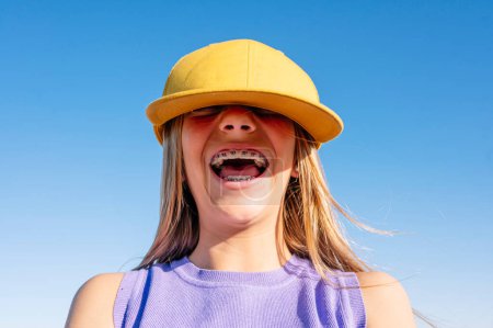 Foto de Feliz adolescente tomando selfies en una gorra amarilla y soporte en sus dientes. - Imagen libre de derechos