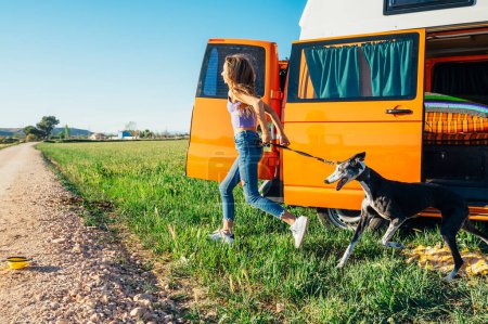 Téléchargez les photos : La fille heureuse avec le chien s'amuse lors d'une merveilleuse journée de camping. Concept de vie Van. - en image libre de droit