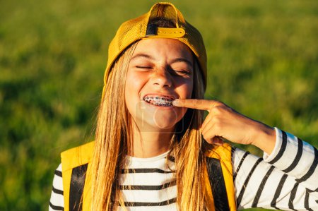 Photo for Portrait of beautiful young blonde girl in a yellow cap and a bracket on her teeth. - Royalty Free Image