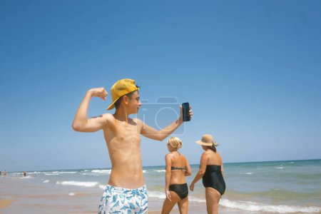 Téléchargez les photos : Adolescente profiter d'une journée fabuleuse à la plage en utilisant un smartphone. - en image libre de droit