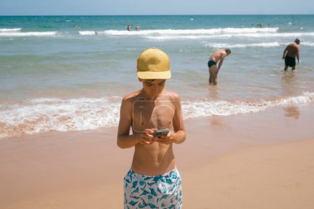 Téléchargez les photos : Adolescente profiter d'une journée fabuleuse à la plage en utilisant un smartphone. - en image libre de droit
