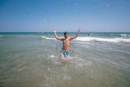 Téléchargez les photos : Adolescente profitant d'une journée fabuleuse à la plage. Elle se baigne dans la mer. - en image libre de droit