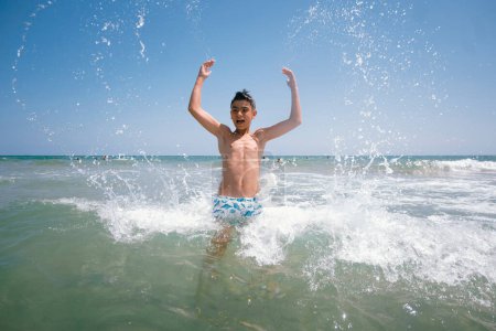 Foto de Adolescente disfrutando de un fabuloso día en la playa. Ella se baña en el mar. - Imagen libre de derechos