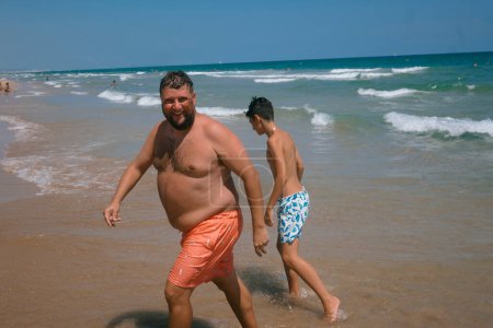 Foto de Adolescente y un hombre adulto disfrutando de un fabuloso día en la playa. - Imagen libre de derechos