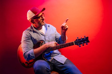 Foto de Hombre tocando la guitarra eléctrica sobre fondo rojo - Imagen libre de derechos