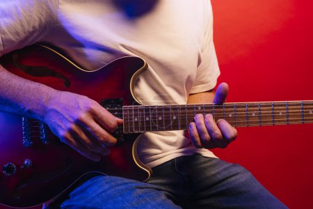 Foto de Hombre tocando la guitarra eléctrica sobre fondo rojo - Imagen libre de derechos