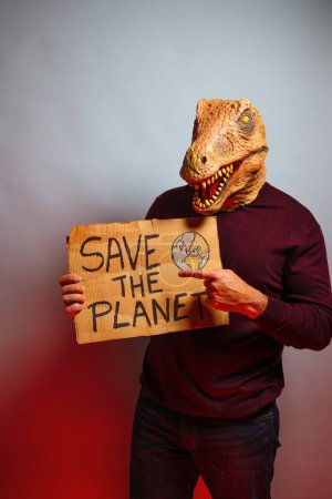 Téléchargez les photos : Homme avec tête de lézard en studio tenant une pancarte en carton qui dit Enregistrer la planète - en image libre de droit