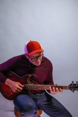 Téléchargez les photos : Homme adulte jouant de la guitare en studio. - en image libre de droit