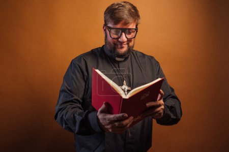 Photo for Portrait of a priest with crucifix and black shirt holding a bible. - Royalty Free Image