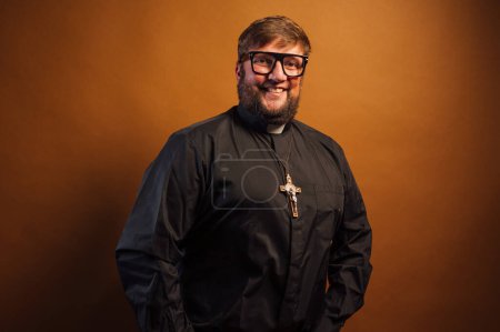 Foto de Retrato de un sacerdote con crucifijo y camisa negra sosteniendo una Biblia. - Imagen libre de derechos