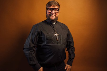 Téléchargez les photos : Portrait d'un prêtre avec crucifix et chemise noire tenant une bible. - en image libre de droit