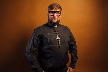 Foto de Retrato de un sacerdote con crucifijo y camisa negra sosteniendo una Biblia. - Imagen libre de derechos