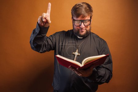 Téléchargez les photos : Portrait d'un prêtre avec crucifix et chemise noire tenant une bible. - en image libre de droit
