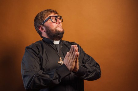 Foto de Retrato de un sacerdote con crucifijo y camisa negra rezando. - Imagen libre de derechos
