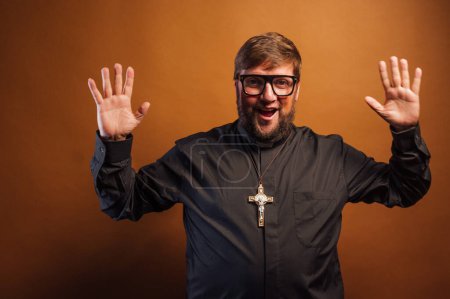 Téléchargez les photos : Portrait d'un prêtre avec crucifix montrant la paume de ses mains. - en image libre de droit