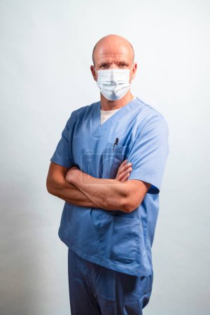 Téléchargez les photos : Portrait d'un physiothérapeute en robe bleu clair et masque facial regardant la caméra en studio. - en image libre de droit