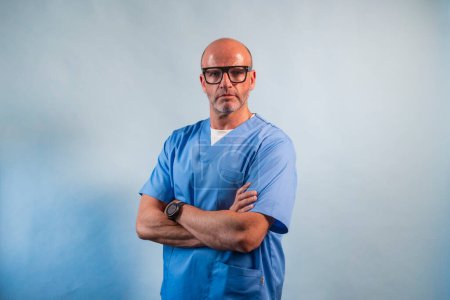 Photo for Portrait of a physiotherapist in light blue gown and glasses looking at camera in studio. - Royalty Free Image