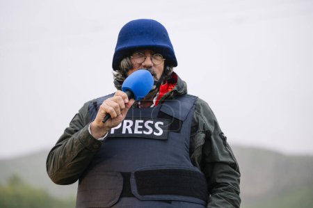 Photo for Press reporter in bulletproof vest holding a microphone. - Royalty Free Image