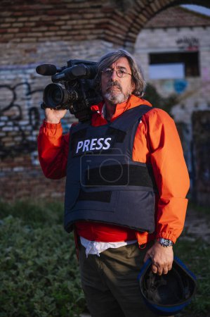 Foto de Reportero con chaleco antibalas sosteniendo una cámara de video - Imagen libre de derechos