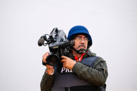 Reportero con chaleco antibalas sosteniendo una cámara de video
