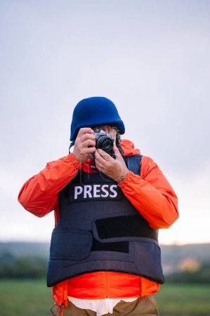 Photo for Reporter in bulletproof vest holding a camera. - Royalty Free Image