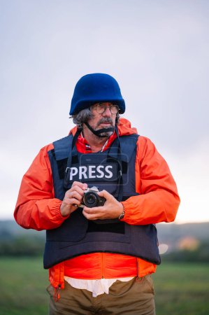 Photo for Reporter in bulletproof vest holding a camera. - Royalty Free Image