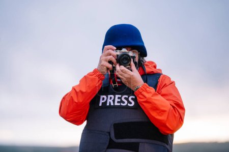 Foto de Reportero con chaleco antibalas sosteniendo una cámara. - Imagen libre de derechos