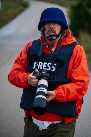 Reportero con chaleco antibalas sosteniendo una cámara.