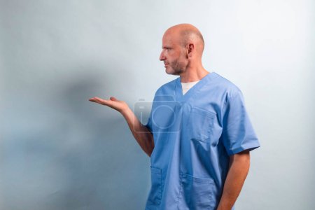 Téléchargez les photos : Portrait d'un physiothérapeute en robe bleu clair pointant sur un côté. - en image libre de droit