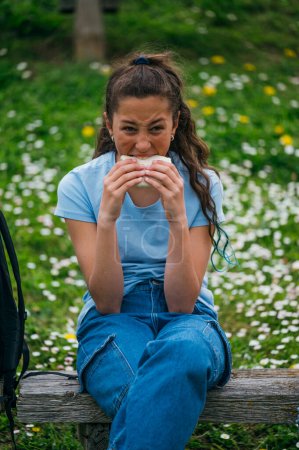 Foto de Hermosa niña comiendo un sándwich en el parque. - Imagen libre de derechos
