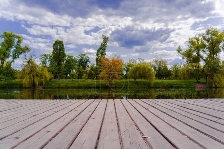 Téléchargez les photos : Nature de l'Ukraine une rivière dans une zone de parc avec une jetée en bois et un ciel bleu vif avec cumulus nuages - en image libre de droit