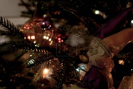 Foto de Un arlequín de juguete en el fondo de un árbol de Navidad festivamente decorado con juguetes y linternas. Ambiente festivo de Año Nuevo. - Imagen libre de derechos