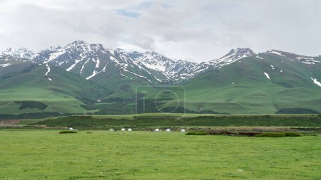 Foto de Kirguistán naturaleza verde paisaje con montañas cubiertas de nieve. Kirguistán es un país sin litoral situado en el centro de Asia, conocido por su terreno accidentado y montañoso y sus verdes praderas.. - Imagen libre de derechos