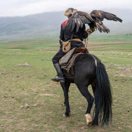 Foto de Issyk Kul, Kirguistán - mayo de 2022: Entrenador de águilas en un caballo y su águila real, experto en el entrenamiento de águilas para la caza, utilizando técnicas tradicionales transmitidas a través de generaciones - Imagen libre de derechos