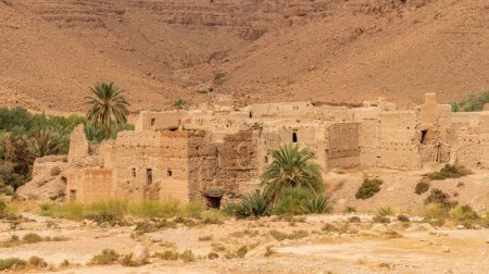 Foto de Casas tradicionales de arcilla marroquí con techos planos, altas paredes de arcilla y pequeñas ventanas en el desfiladero de la montaña del Atlas junto al río Ziz, Marruecos - Imagen libre de derechos