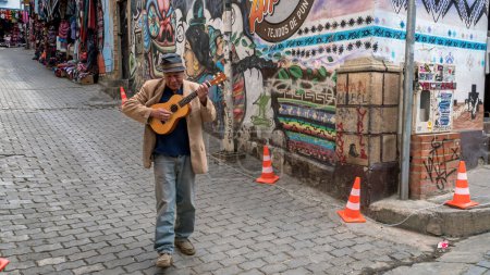 Téléchargez les photos : Cusco, Pérou - 24 octobre 2023 : Un Péruvien jouant de la guitare et chantant, marchant dans la rue de la ville - en image libre de droit
