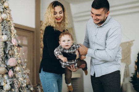 Foto de Retrato de familia feliz de padre madre y pequeño hijo rizado celebrando la Navidad juntos en casa. Concepto de Nochevieja. - Imagen libre de derechos