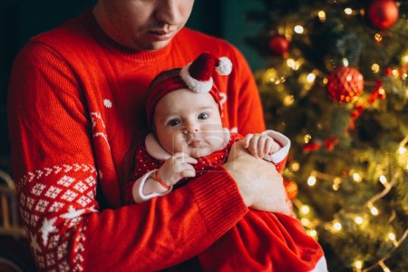 Foto de Fragmento de un retrato de un padre y una niña con ropa de Navidad tradicional cerca del árbol de Navidad - Imagen libre de derechos