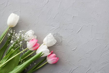 Photo for Pink tulips and white gypsophila flowers bouquet on a stylish gray stone background. Mothers Day, birthday celebration concept. Copy space for text. Mockup - Royalty Free Image